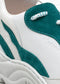 Close-up of a white and teal V3 Leather Color Mix Emerald low top sneaker showing the lace, textured fabric, and logo detail.