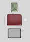 Flat lay of a tablet, M Leather Pouch Bordeaux, airpods, pen, and notebook with a green checkered cover on a light gray background, featuring stylish leathergoods.