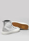 A pair of TH0011 by Joana high-top canvas shoes with white uppers and rubber soles, one lying flat showing the hexagonal pattern on the sole.