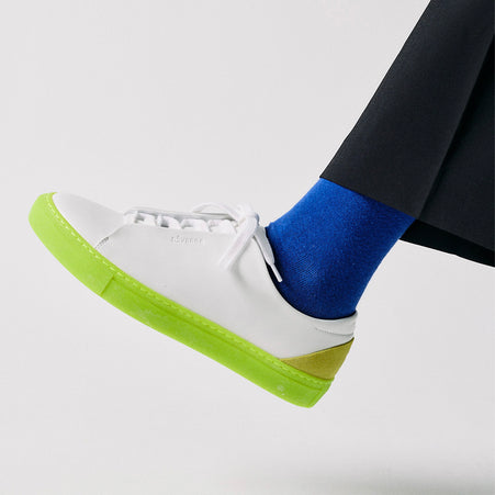 Low top white sneakers with a bright sole by Diverge, promoting social impact and custom shoes.