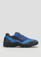 The L0015 by Iara is a blue and black athletic shoe with a layered design, featuring thick tread soles and lace-up closure, handcrafted from premium Italian leathers, displayed against a plain gray background.
