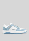 The M0011 by Serifo is a white and light blue sneaker with a flat sole, featuring a lace-up design and accented with perforated details and light blue suede patches on a gray background. This retro-future sneaker is handcrafted in Portugal using premium Italian leathers for ultimate quality.