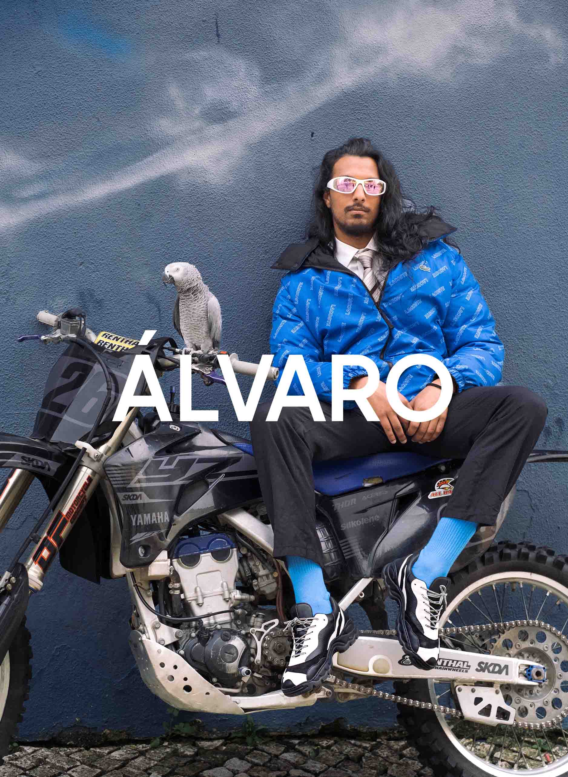 Un hombre llamado Álvaro sentado en una motocicleta con un pájaro, vestido Diverge sneakers, promoviendo el calzado personalizado y el impacto social a través del proyecto Imagine.