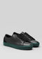 V49 Black W/ Forest Green sneakers, handcrafted in Portugal from premium Italian leathers, feature black leather with green rubber soles and are displayed on a gray background.