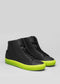 The V51 Black W/ Yellow high-top sneakers are made from premium Italian leather, featuring striking neon green soles, and are displayed against a plain gray background.