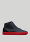 The V49 Deep Blue W/ Red, a handcrafted high-top sneaker from Portugal, showcases a textured leather finish and a bright red rubber sole against a plain gray background.