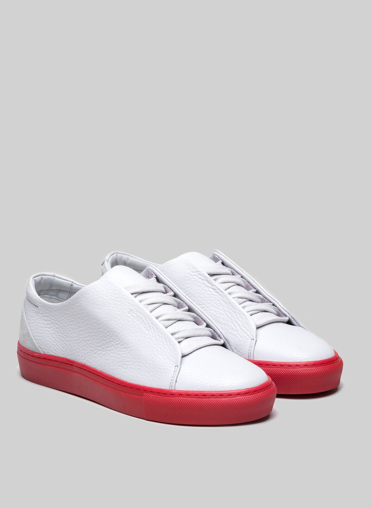 Un par de low top custom blancas sneakers con suela roja de Diverge.