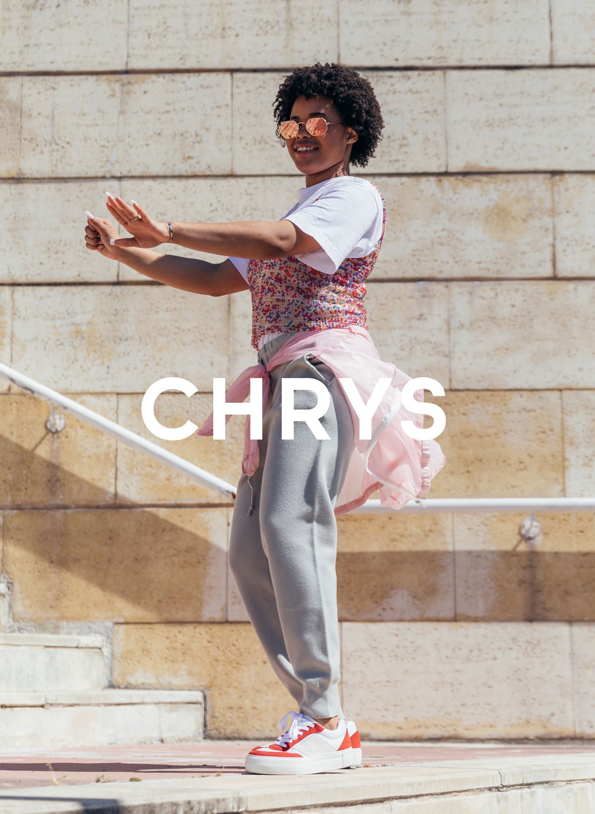  Chrys con gli occhiali da sole e una camicia rosa che balla, indossa Diverge sneakers Promuovere l'impatto sociale e le scarpe personalizzate attraverso il progetto Imagine.