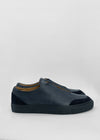 Un paio di SO0015 Deep Blue Floater slip-on sneakers con una spessa suola nera, visualizzati su uno sfondo grigio chiaro.