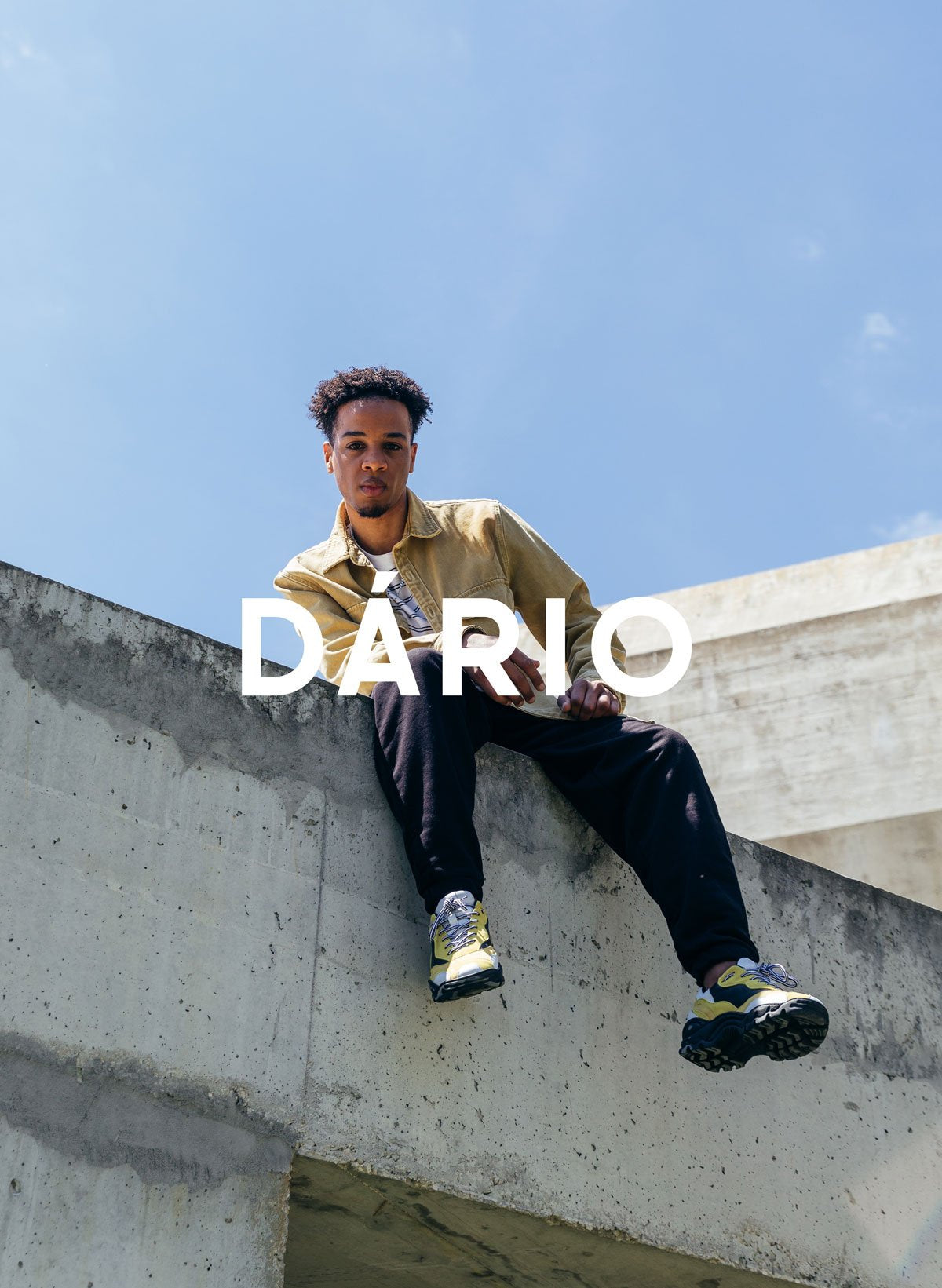 Dário assis sur un mur en portant Diverge sneakers, en mettant en avant l’impact social et les chaussures personnalisées à travers le projet Imagine.