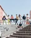 A group of young people sitting on a hadrail, wearing Diverge sneakers, promoting social impact and custom shoes throught the imagine project.