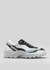 The L0020 by Lara is a premium handcrafted chunky white sneaker with black and light blue accents, featuring a thick sole and blue laces, crafted from exquisite Italian leathers, set against a plain gray background.