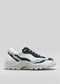 The L0020 by Lara is a premium handcrafted chunky white sneaker with black and light blue accents, featuring a thick sole and blue laces, crafted from exquisite Italian leathers, set against a plain gray background.