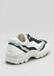 The L0020 by Lara are premium handcrafted sneakers made from Italian white leather. They feature black, navy, and light blue accents with a thick, textured sole and decorative wavy side patterns for a sophisticated look.