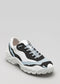 The L0020 by Lara is a premium handcrafted sneaker with color block Italian leathers in white and black, featuring light gray accents, blue laces, and a thick sole on a plain background.