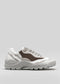 The L0021 by Hanin is a chunky, handcrafted sneaker featuring white, grey, and brown panels on a thick, textured sole, displayed against a plain grey background.