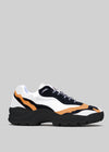 The L0022 by Alexandre is a black, white, and orange sneaker with premium handcrafted Italian leather and a chunky black sole set against a gray background.