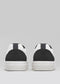 Back view of the N0019 by Ana Júlia, a pair of black and white low-top sneakers with white soles on a gray background. These are handcrafted in Portugal using premium Italian leathers, combining style and quality.