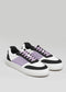 Ana Júlia's N0019 sneakers feature black, white, and purple Italian leather with purple laces and white soles against a gray backdrop.