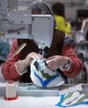A woman sewing on fabric, part of responsible production for custom shoes by a shoe maker.