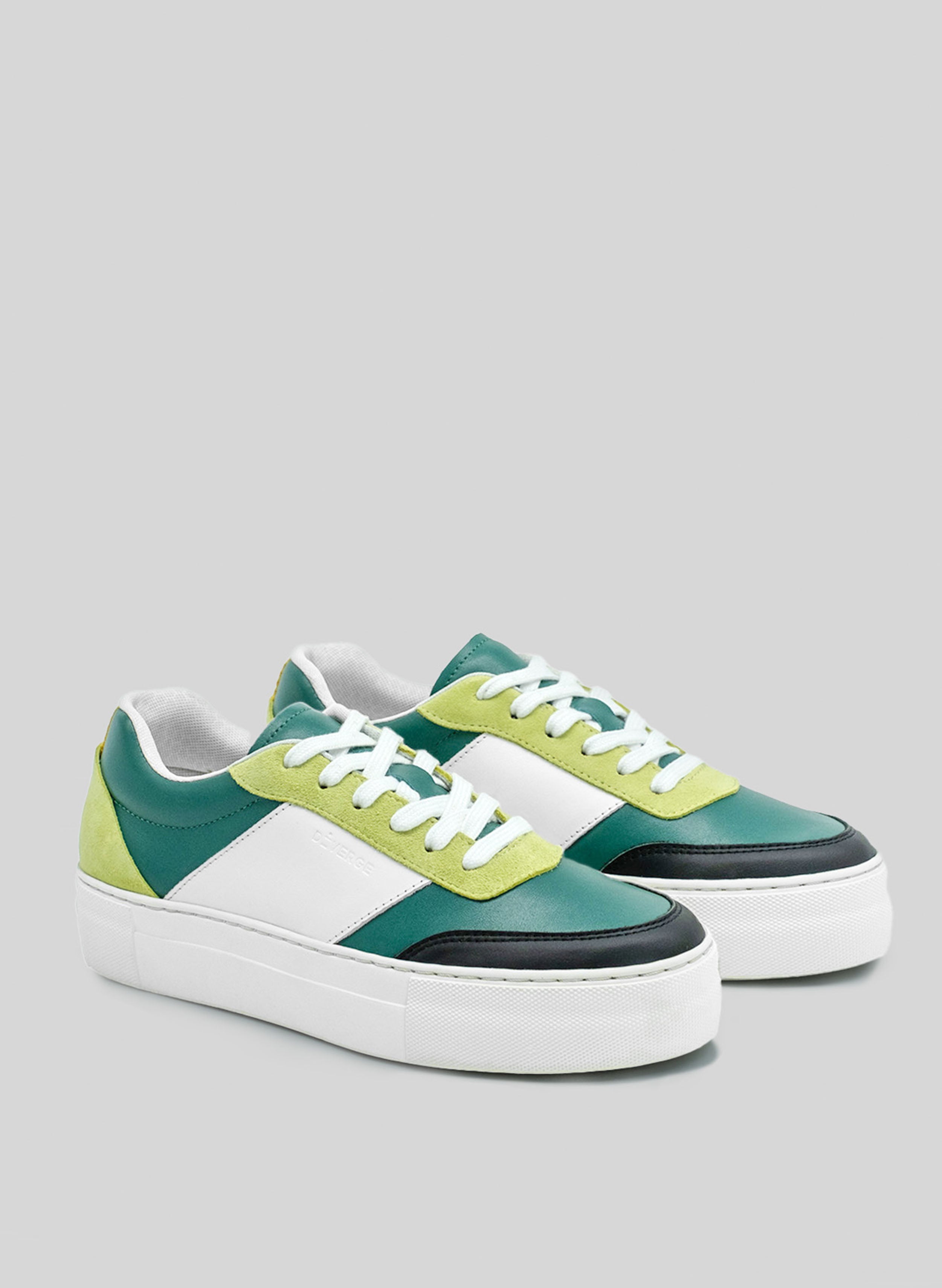 Un par de zapatillas personalizadas de color verde, blanco, negro y lima sneakers con suela blanca, fabricadas por Diverge, que promueven un impacto social.