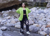 Una donna in giacca verde e pantaloni neri in piedi sulle rocce, indossa Diverge sneakers , promuove l'impatto sociale e le scarpe personalizzate attraverso il progetto imagine.