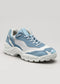 The L0024 by Bárbara is a light blue and white athletic shoe with a chunky sole, showcasing wavy design patterns and matching laces, crafted from premium Italian leathers, set against a plain gray background.