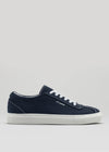 Introducing the V3 Marine: a handcrafted canvas sneaker in navy blue, featuring white laces and a sleek rubber cupsole. Made in Portugal, this stylish shoe includes elegant branding on the side set against a plain background.