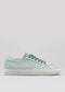 Introducing the V6 Sage Green, a versatile sneaker crafted with premium canvas featuring a light green hue, complemented by a white sole and blue laces against a plain background.