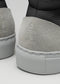 Close-up of the V56 Black W/ Bone sneakers' back, showcasing gray suede and black leather accents with textured gray rubber soles. Handcrafted in Portugal using premium Italian leathers, they embody style and exceptional craftsmanship.