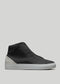 The V56 Black W/ Bone high-top sneaker, handcrafted in Portugal, boasts a smooth leather upper and gray suede heel accent. Made with premium Italian leathers and set on a white rubber sole, it's displayed on a light gray background.