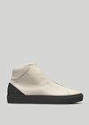 The V57 Beige Floater W/ Black is a high-top sneaker crafted with off-white premium Italian leathers, featuring a black heel and sole. Handcrafted in Portugal, this shoe epitomizes exquisite craftsmanship, shown from the side against a light gray background.