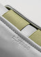 Nahaufnahme eines V17 Grey W/ Green Low-Top-Sneakers mit olivgrünen elastischen Details und geprägtem "deverge"-Branding auf dem Leder.