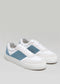 The N0017 by Raquel are handcrafted sneakers featuring premium Italian leathers in white with light blue and gray panels, white laces, and a thick sole set against a plain gray background.