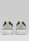Rear view of the V30 Plaster & Deep Blue handcrafted sneakers, showcasing a navy blue and gray design with a yellow heel tab and white soles, made from premium Italian leathers against a plain background.