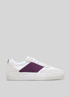 The V37 White W/ Plum sneakers feature a handcrafted design with white and purple side panels, white laces, and a gray background.