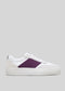 The V37 White W/ Plum sneakers feature a handcrafted design with white and purple side panels, white laces, and a gray background.