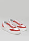 A pair of N0001 by Chrys low top sneakers in red and white with white laces on a gray background.