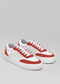 A pair of N0001 by Chrys low top sneakers in red and white with white laces on a gray background.