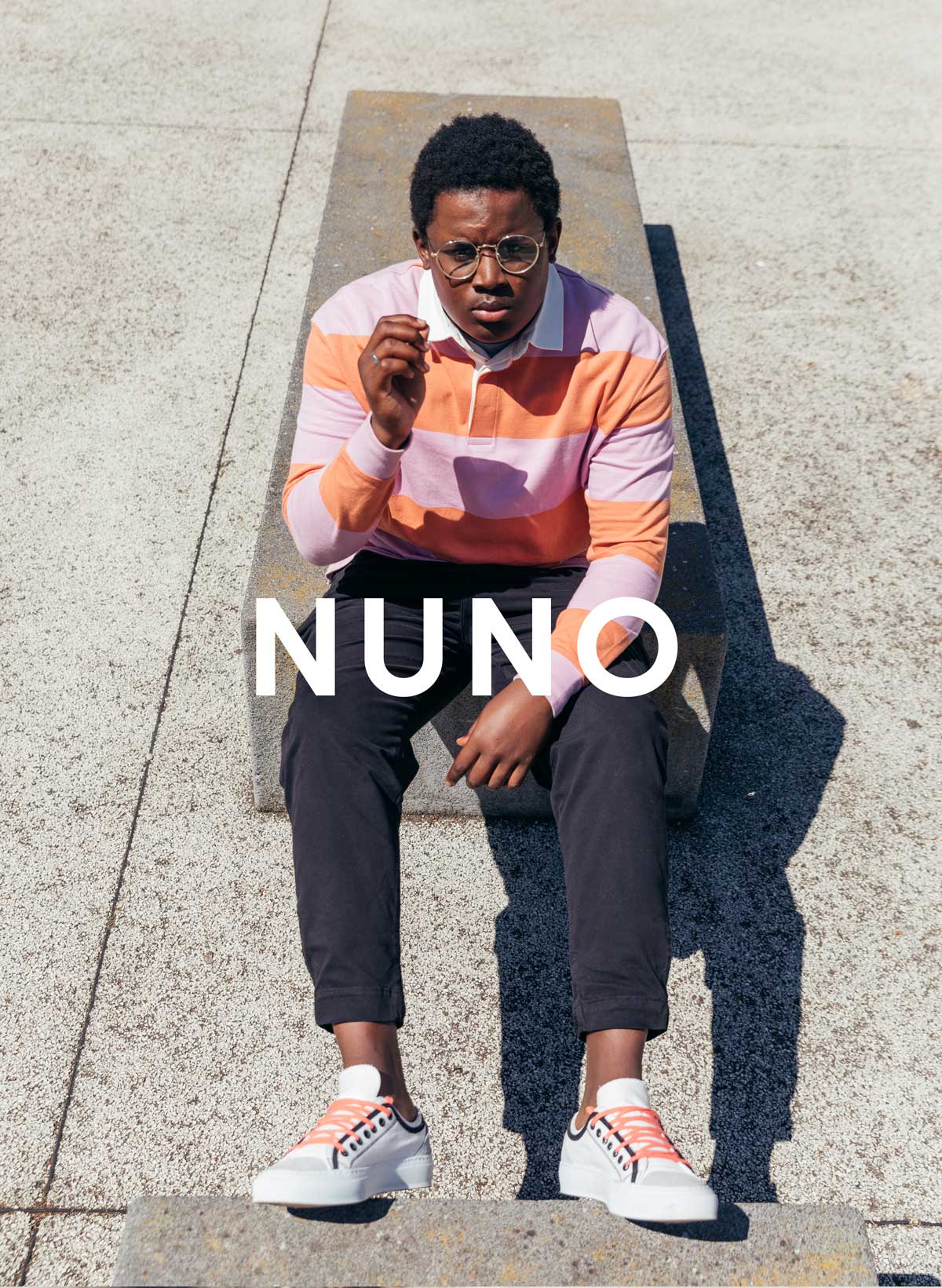 Nuno seduto su un muro, indossando sneakers Da Diverge, con un impatto sociale attraverso il progetto Imagine.