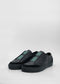Une paire de SO0014 Black Floater slip-on sneakers avec des bandes velcro sur un fond blanc.