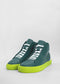 Un par de MH0080 Green W/ Yellow sneakers con parte superior de cuero verde y suela de color lima brillante, con cordones blancos, sobre un fondo neutro.