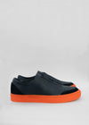 A pair of SO0016 Black W/ Orange slip-on sneakers, displayed against a light gray background.