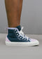 Person wearing Stella's TH0027 premium high-top canvas sneakers with a dark blue and pink design, white laces, and white sole, standing on gray ground; these stylish shoes are expertly handcrafted in Portugal.