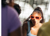 Eine Frau mit Sonnenbrille, die vor einer Gruppe von Menschen steht. Sie trägt Diverge sneakers  und wirbt für soziale Auswirkungen und maßgeschneiderte Schuhe im Rahmen des imagine-Projekts.