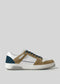 The V15 Beige W/ Ocean Blue sneaker features a white leather upper with premium Italian brown suede accents, a teal heel patch, and black laces, embodying retro-future design against a plain gray background.
