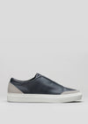 A side view of the V23 Deep Blue W/ Plaster slip-on sneaker, featuring a dark blue design with a white sole and gray accents at the heel and toe, handcrafted in Portugal, set against a light gray background.