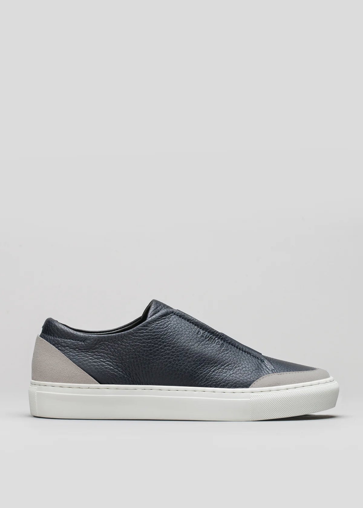 A side view of the V23 Deep Blue W/ Plaster slip-on sneaker, featuring a dark blue design with a white sole and gray accents at the heel and toe, handcrafted in Portugal, set against a light gray background.