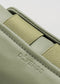 Close-up of the V24 Pine W/ Olive, a green leather and fabric item with embossed "DVERGE" text on the side, handcrafted in Portugal.