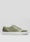 The V24 Pine W/ Olive is a made-to-order slip-on sneaker in Portugal, featuring a premium smooth green leather upper with darker green accents at the heel and toe, and a white rubber sole.